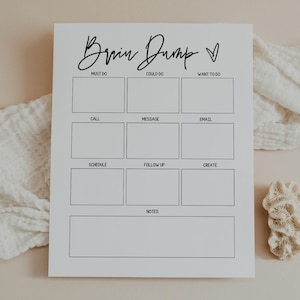 May include: A white Brain Dump notepad with sections for Must Do, Could Do, and Want to Do. Additional sections include Call, Message, Email, Schedule, Follow Up, Create, and Notes. The notepad is on a neutral background.