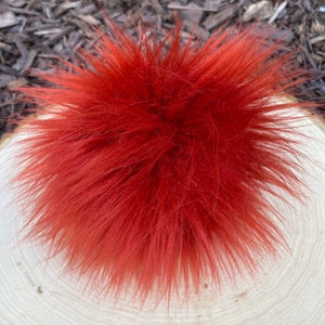 May include: A bright red fluffy pom pom, perfect for adding a pop of color to any project.
