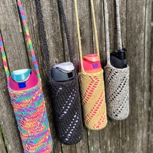 Peut inclure: Quatre porte-bouteilles d'eau en rang, chacun avec une palette de couleurs différente. Les supports sont faits de fil tricoté ou crocheté et ont une sangle pour le transport. Les bouteilles sont dans des tons de rose, noir, beige et gris.