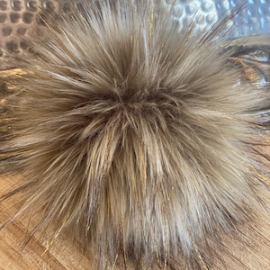 May include: A fluffy brown faux fur pom pom with gold glitter strands.