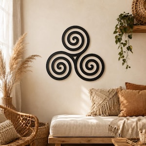 May include: Black metal wall art featuring a triple spiral design. The artwork is mounted on a cream-colored wall, complementing the neutral tones of the room's decor. The spirals are a bold, minimalist statement piece.