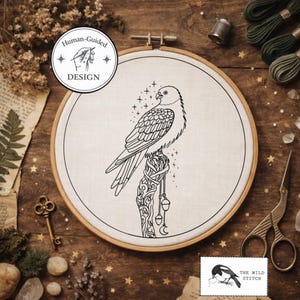 May include: An embroidery hoop featuring a black and white illustration of a bird perched on a decorated branch. The design includes stars, moons, and the text "Human-Guided DESIGN". The Wild Stitch logo is in the bottom right corner.