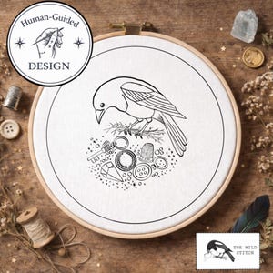 May include: A black and white embroidery hoop featuring a bird perched above sewing notions. The design includes a key, thimble, buttons, and the text "Human-Guided DESIGN". The Wild Stitch logo is in the lower right.
