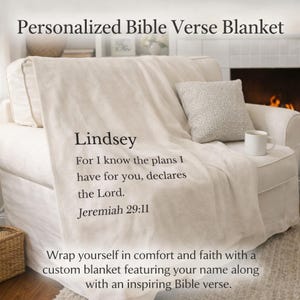 May include: Cream-colored blanket draped over a white sofa, featuring the name "Lindsey" and a Bible verse from Jeremiah 29:11. The blanket is personalized and designed for comfort and faith. A small pillow and a mug are also visible.