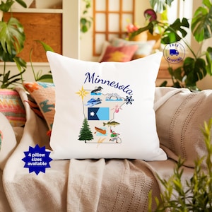 May include: White pillow with a Minnesota state outline design. The design includes illustrations of a loon, a snowflake, a pine tree, and a fisherman. The word "Minnesota" is written in blue script. The pillow is on a couch.
