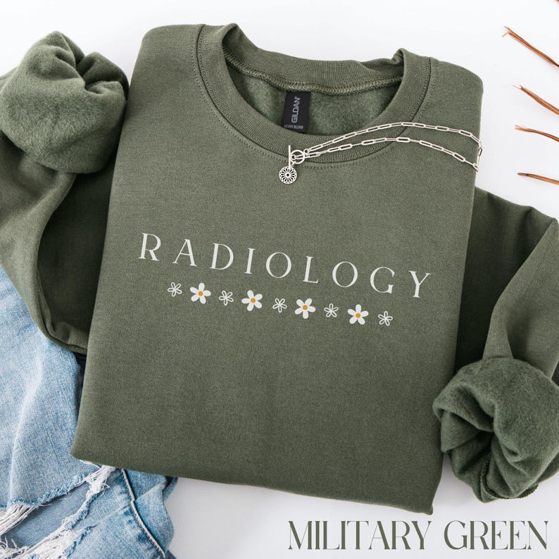 May include: A green sweatshirt with the text "RADIOLOGY" in white lettering and a row of small white flowers underneath. The sweatshirt is on a blue denim background.