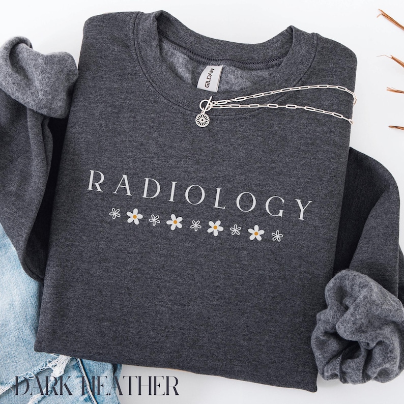 May include: Dark heather grey sweatshirt with the text "RADIOLOGY" in white lettering and a row of white daisies with yellow centers below the text.