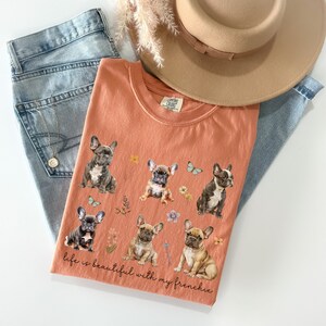 May include: A peach-coloured t-shirt with a graphic of five French Bulldogs and the text "life is beautiful with my frenchie".