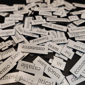May include: White rectangular tiles with black text on a black background. The tiles contain words such as 'commerce', 'team', 'Tuesday', 'copy', 'drill down', 'meeting', 'work', 'budget', 'boss', 'capable', 'paste', 'political', 'touch', 'base', 'for', 'network', 'upgrade', 'FYA', 'divers', 'calculate', 'and', 'document'.