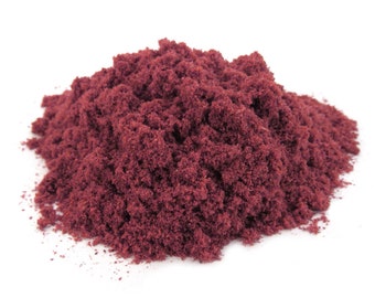 May include: A pile of deep red powder, likely a food coloring or ingredient, on a white background.