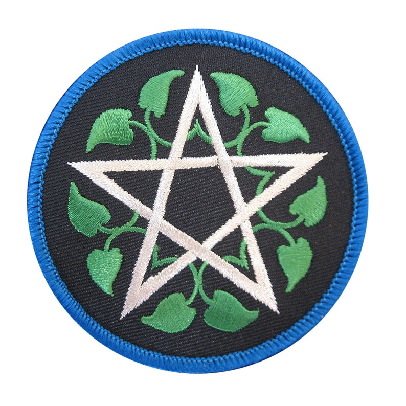 May include: Round black patch with a white pentagram design, surrounded by green leaves and vines. The patch has a blue border. The design is embroidered on the patch.