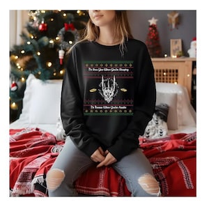 May include: Black sweatshirt with a festive design. The design includes the text "He Sees You When You're Sleeping" and "He Knows When You're Awake" with a skull and ring graphic. The sweatshirt has a Christmas theme.