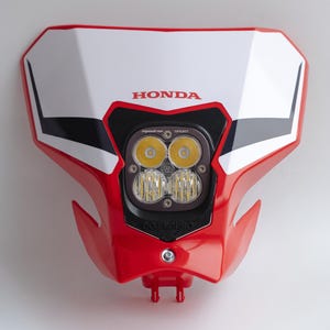 May include: Red and white motorcycle headlight assembly with the Honda logo. The assembly features a black and silver LED light array with four lights. The headlight is designed for off-road use.