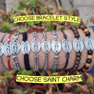 Può includere: Una varietà di stili di braccialetti con un ciondolo d'argento con un'immagine religiosa. Scegli il tuo stile di braccialetto e il tuo ciondolo di santo. Il testo "Scegli lo stile del braccialetto" e "Scegli il ciondolo del santo" è visibile nell'immagine.