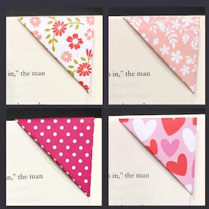 May include: Four different corner bookmarks with various patterns. The top left bookmark has a white background with red and green floral designs. The top right bookmark has a pink background with white floral designs. The bottom left bookmark has a pink background with white polka dots. The bottom right bookmark has a pink background with white and red hearts.