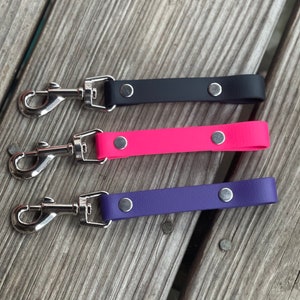 May include: Three dog leashes with silver swivel clips. The leashes are made of black, pink, and purple leather.