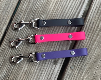 May include: Three dog leashes with silver swivel clips. The leashes are made of black, pink, and purple leather.