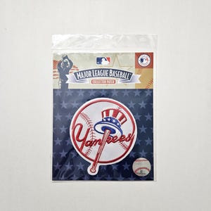 May include: A Major League Baseball collector patch featuring the New York Yankees logo. The patch is round with a baseball bat and the word "Yankees" in red. The background is white with a blue and red Uncle Sam hat design.