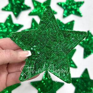 May include: Green sparkly star-shaped fabric patches. The stars are made of sequins and have a felt backing.