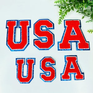 May include: Red felt letters spelling "USA" with a blue outline. The letters are in a vintage style and have a fuzzy texture.