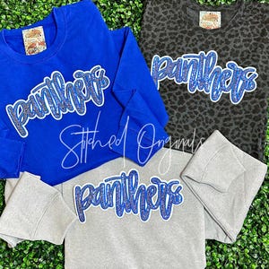 May include: Three sweatshirts with the word "Panthers" in blue rhinestones. The sweatshirts are in blue, gray, and black with a leopard print.