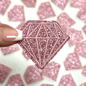 May include: A pink glitter diamond-shaped sticker with a white outline. The sticker is on a white background with other pink glitter diamond-shaped stickers.