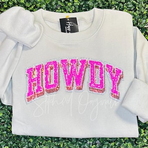 May include: A light gray sweatshirt with the word "HOWDY" in pink and silver glitter letters.