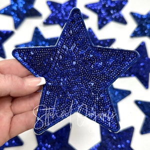 May include: Blue sequin star-shaped patches. The stars are approximately 3 inches in diameter and have a soft, felt-like backing.