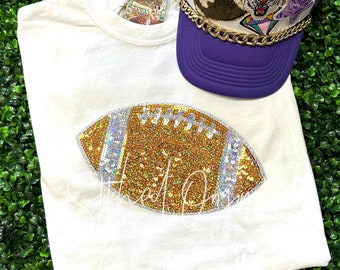 May include: White t-shirt with a gold and silver sequined football design.