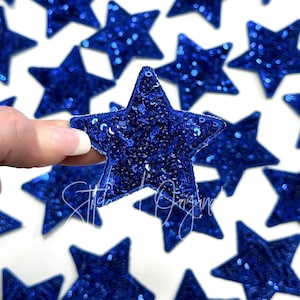 May include: A close-up of a blue sparkly star-shaped patch. The patch is made of sequins and is perfect for adding a touch of sparkle to any project.