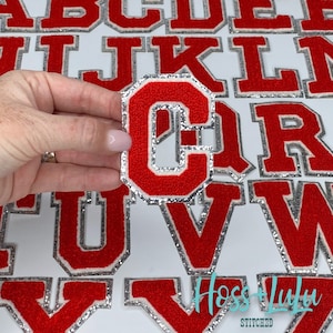 May include: Red felt letter patches with a silver glitter trim. The letters are in a collegiate font style. The letters are C, R, U, V, and Y.