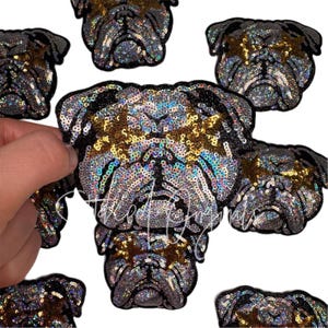 May include: Embroidered patches featuring a bulldog design. The patches are covered in silver and gold sequins, with black accents. The patches are in the shape of a bulldog's head and face.