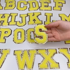 May include: A set of yellow felt letters with gold glitter trim. The letters are in uppercase and range from A to Z. The letters are perfect for crafting projects, scrapbooking, or adding a personal touch to gifts.