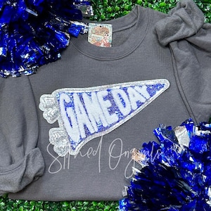 May include: A gray sweatshirt with a white and blue sequined pennant that says "Game Day".