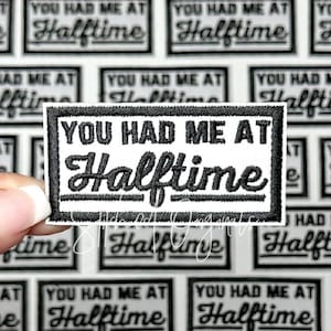 May include: A black and white iron-on patch with the text "You Had Me At Halftime" in a white rectangle with a black border.