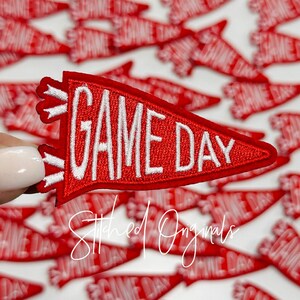 May include: Red felt pennant with white stitching that reads "GAME DAY".