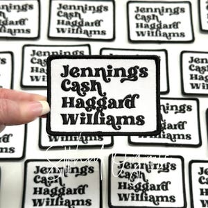 May include: A white iron-on patch with black embroidered text that reads "Jennings Cash Haggard Williams".