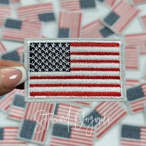 May include: A white and red embroidered American flag patch with a gray border. The patch is surrounded by other American flag patches.