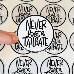 May include: White and black circular patch with the text "NEVER lost a TAILGATE" in a handwritten style. The patch is surrounded by a black border. The image shows multiple patches.