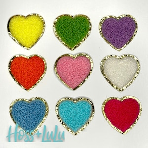 May include: Nine felt heart-shaped patches with gold trim. The colors are yellow, green, purple, orange, pink, white, blue, turquoise, and red.