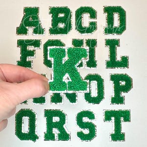 May include: Green felt letters with a white outline. The letters are A, B, C, D, F, G, I, K, L, N, O, P, Q, R, S, and T.