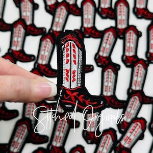 May include: A close-up of a red and white embroidered boot patch. The boot is black with red and white stitching. The boot is surrounded by other similar patches.