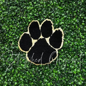 May include: Black paw print with a gold glitter outline. The paw print is on a green background.