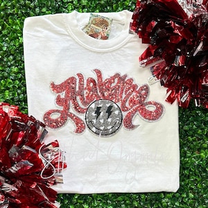 May include: White t-shirt with a red sequined design that says "Halestorm" with a silver smiley face with lightning bolts in the middle.