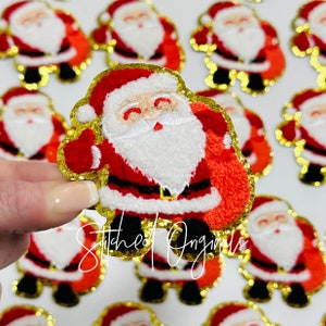 May include: A collection of red and white felt Santa Claus patches with gold glitter trim. The patches are approximately 2 inches tall and feature a white beard and a red bag.