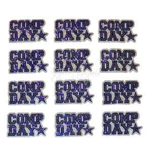 May include: A collection of twelve sequined patches. Each patch features the words "COMP DAY" in a bold, dark blue font, outlined with silver sequins. A star is next to the word "DAY".
