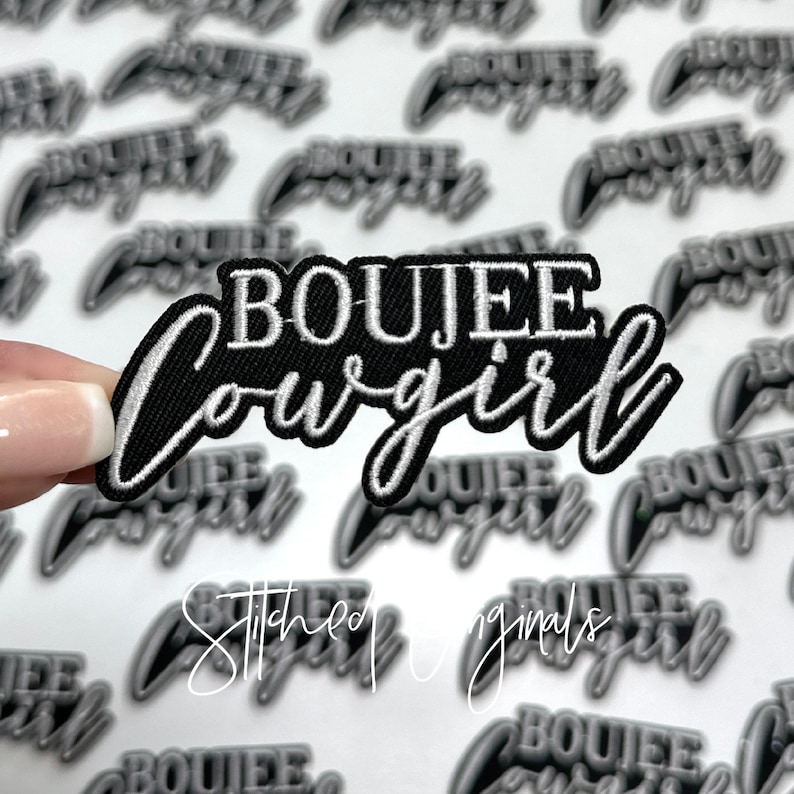 May include: A black and white embroidered patch with the text "BOUJEE cowgirl" in white lettering. The patch is on a white background.