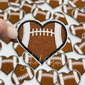 May include: A brown and white heart-shaped patch with an embroidered football design. The patch is surrounded by other heart-shaped patches with the same design.