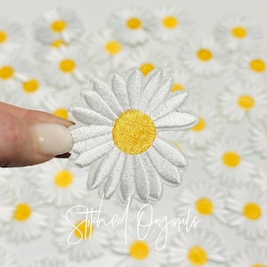 May include: White felt daisy flower patch with a yellow center. The patch is approximately 2 inches in diameter.