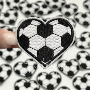 May include: A black and white soccer ball design in the shape of a heart. The heart is made of felt and is about 2 inches wide.
